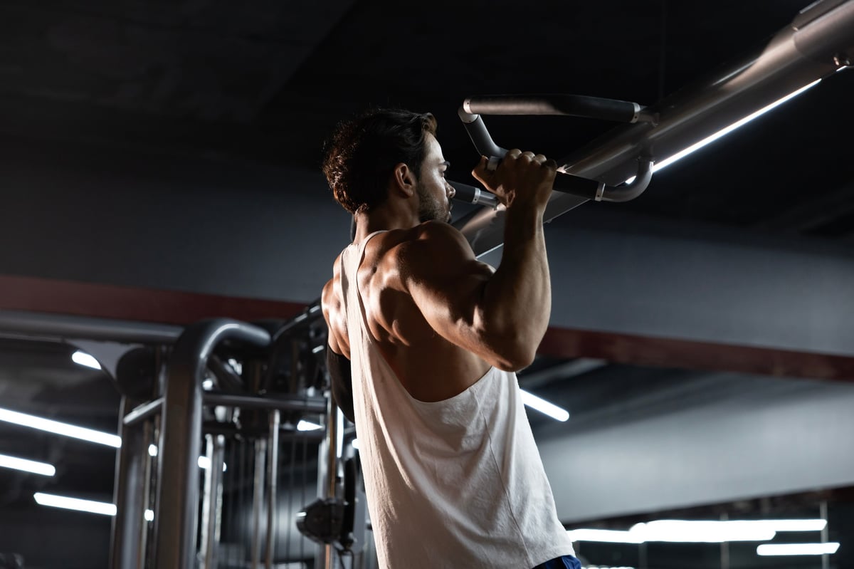 Portrait of caucasian muscular sport man with perfect abs and bicep muscle inside gym with dark background for exercise and workout in high contrast low key lighting studio set