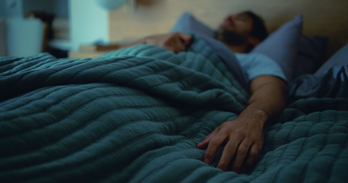Sleeping, tired and man in bed at night for resting, dreaming and exhausted for nap in home